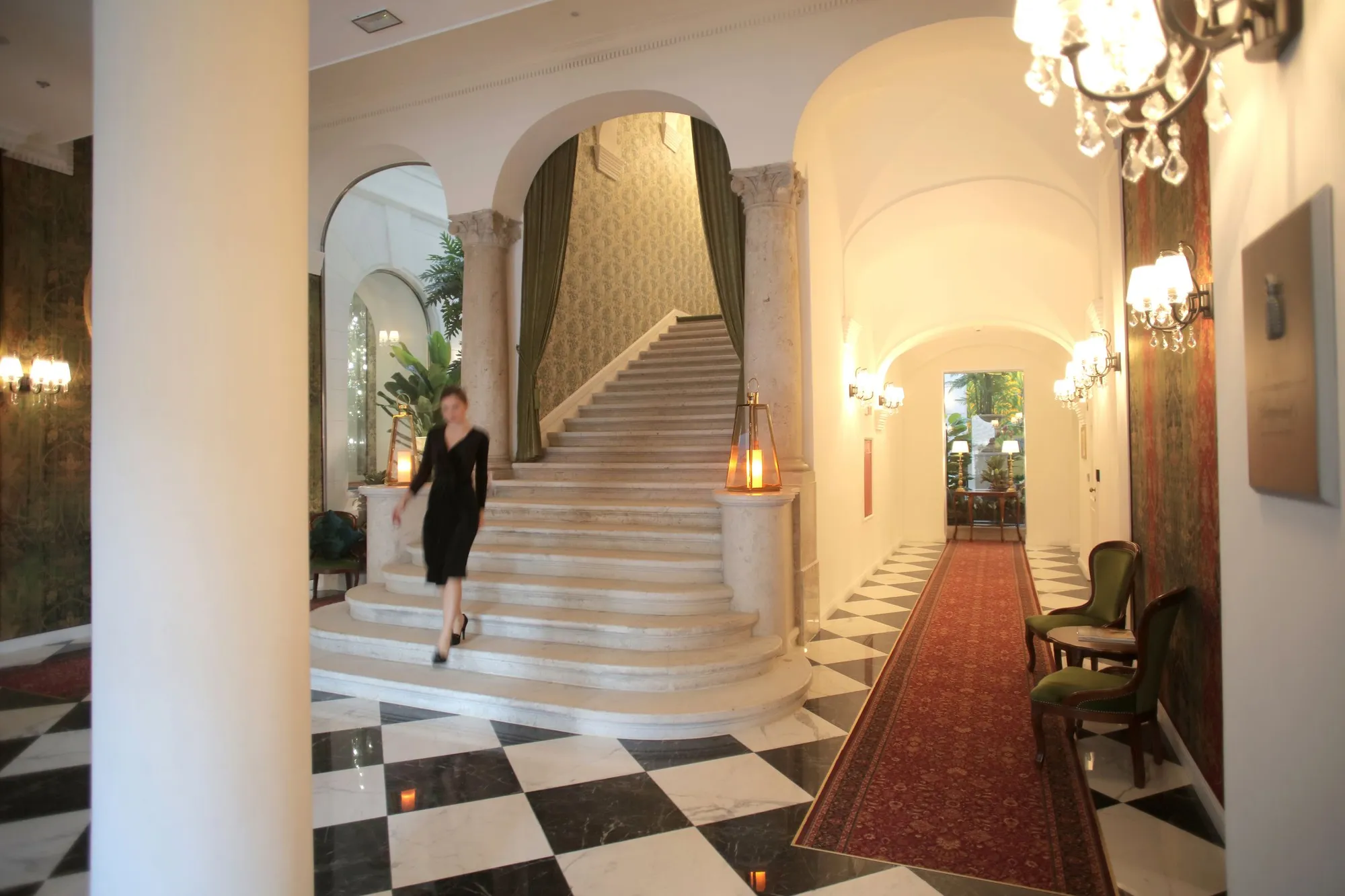 A guest descending the marble staircase of a classic hotel lobby